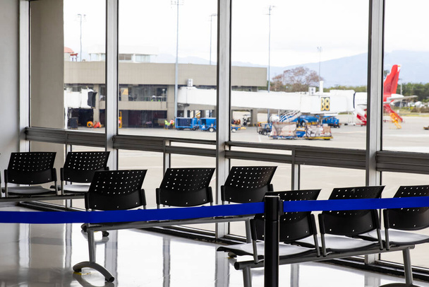 COVID-19 salgını sırasında havaalanında boş bekleme odası. Sandalyelerde sosyal uzaklık işaretleri var. - Fotoğraf, Görsel