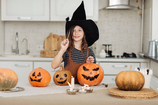 Šťastný Halloween. Roztomilá holčička v kostýmu čarodějnice s vyřezávanou dýní. Šťastná rodina se připravuje na Halloween. dívka světla svíčky. - Fotografie, Obrázek