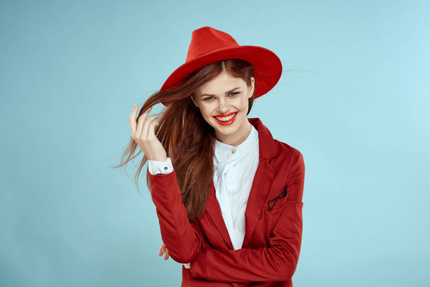 Красивая женщина в красной куртке шляпы красные губы длинные волосы очарование синий фон - Фото, изображение