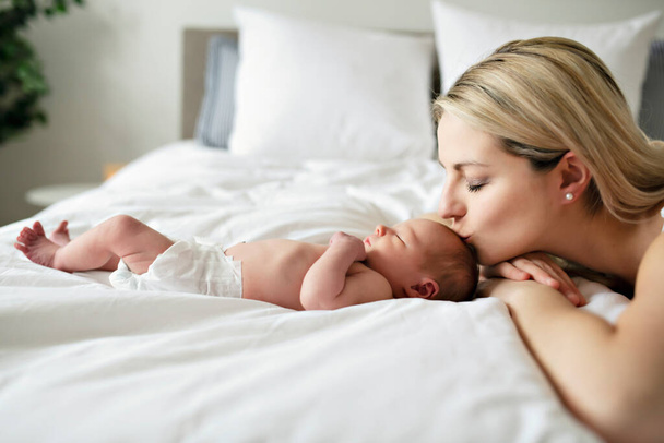 A woman with a newborn baby in bed kiss her - Zdjęcie, obraz