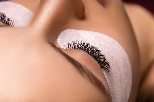 Eyelash Extension Procedure. Close up view of beautiful female eye with long eyelashes, smooth healthy skin. - Фото, зображення