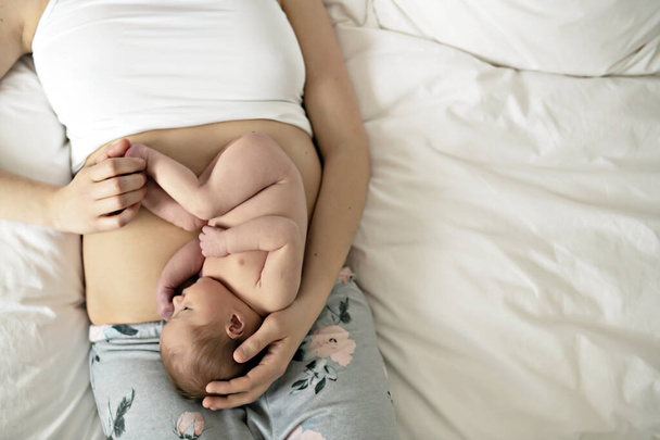A mother with a newborn baby in bed on belly like fetus - Φωτογραφία, εικόνα