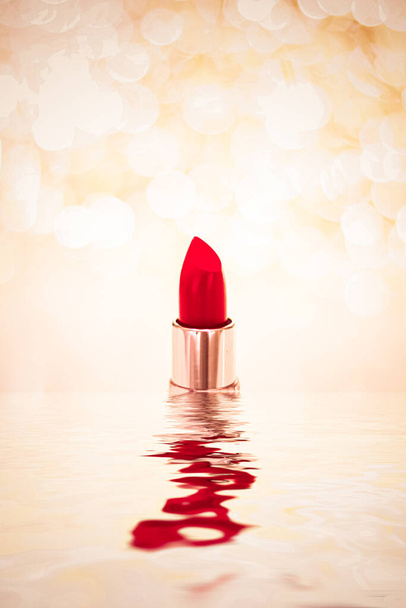 Rode lippenstift op gouden achtergrond, make-up en cosmetisch product - Foto, afbeelding