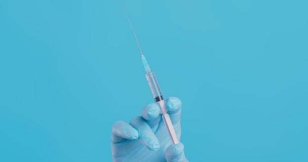 Colpo ravvicinato di siringa con vaccino tenuta in mano dal medico, spingendola lentamente, tirando fuori bolle d'aria - Filmati, video