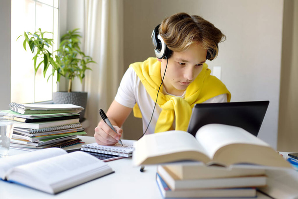 Tennager boy study at home. Online education and distance learning for children. School boy doing his physics homework using gadgets. Lectures and lessons on the internet for high school students - Foto, Imagem
