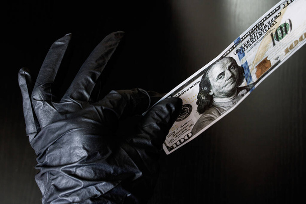 A hand in a black glove holds a dollar - Zdjęcie, obraz