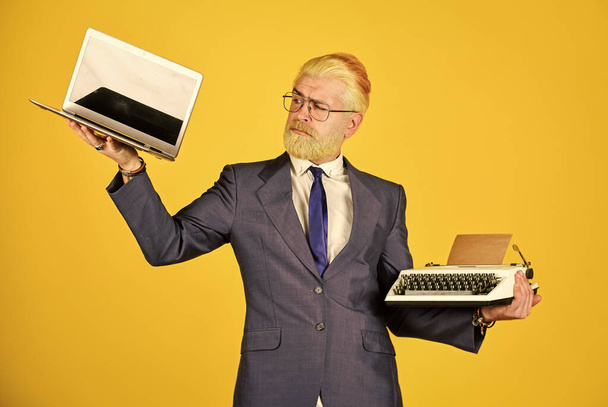 Buy new modern gadget. Useful device. Modern instead outdated. Connoisseur of vintage values. Typewriter against laptop. Businessman use modern technology. Man dyed beard hair yellow background - Фото, зображення