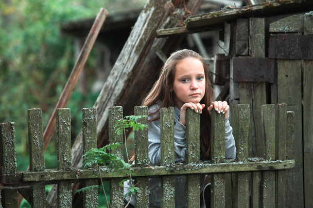 Teengirl στέκεται κοντά vintage αγροτικό φράχτη στο χωριό. - Φωτογραφία, εικόνα