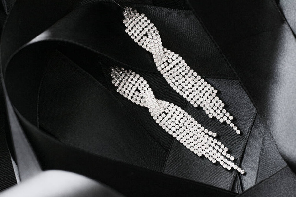 Роскошные бриллиантовые серьги на черной шелковой ленте в качестве фона, ювелирные изделия и модный бренд - Фото, изображение