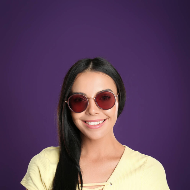 Beautiful woman wearing sunglasses on purple background - Foto, afbeelding