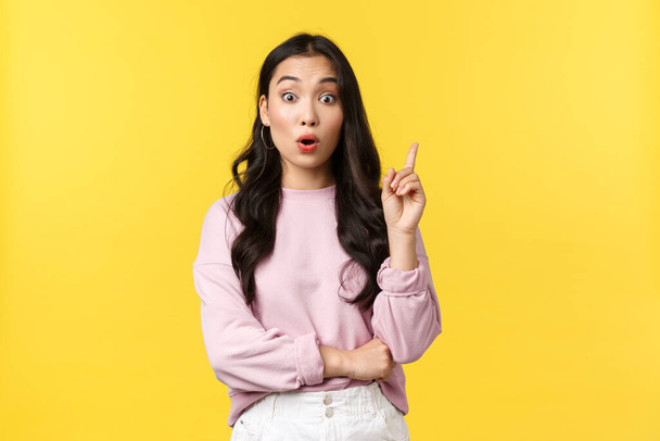 People emotions, lifestyle and fashion concept. Thoughtful excited stylish asian woman have idea, raising index finger and say suggestion, have plan, think-up solution, standing yellow background - Foto, immagini