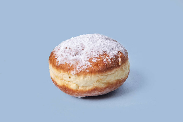 One sweet doughnut with filling. Isolated on a blue background. - 写真・画像