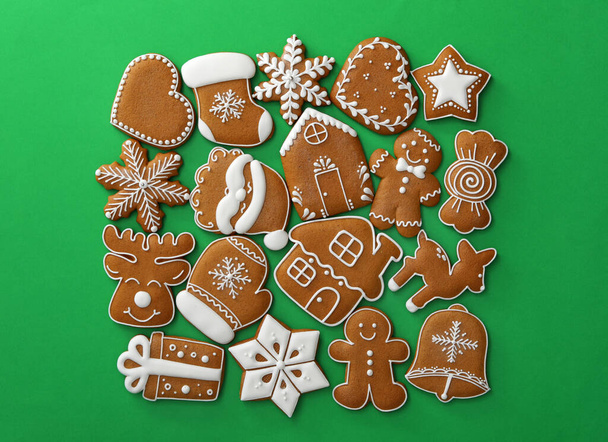 Different Christmas gingerbread cookies on green background, flat lay - Φωτογραφία, εικόνα