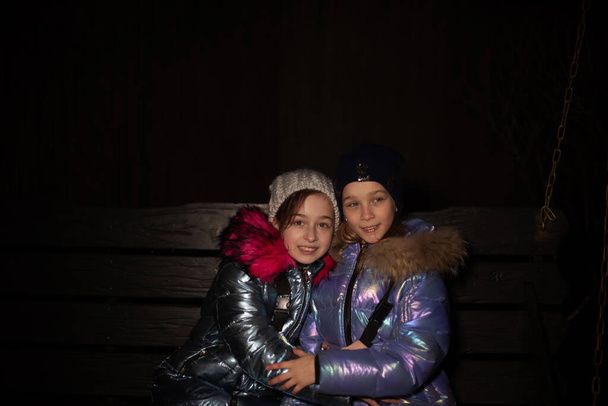 Twee mooie jonge vriendinnen wandelen in de winter. Twee tienervriendinnen in winterjasjes - Foto, afbeelding