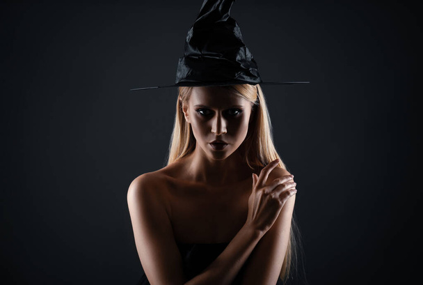 Witch in black hat on dark background. Scary fantasy character - Φωτογραφία, εικόνα