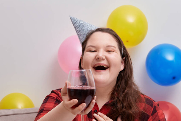 A young happy woman celebrates her birthday with a glass of red wine. - Foto, Bild