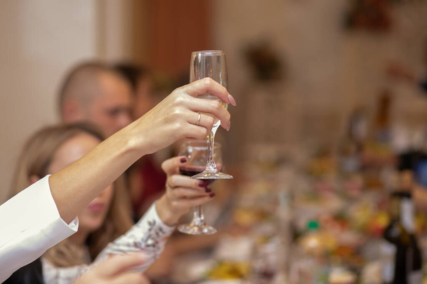 休日パーティーのコンセプト。お酒のグラスで手を閉じる美しいマニキュア。シャンパンを飲みながら乾杯します。テキストと広告のためのフリースペース - 写真・画像