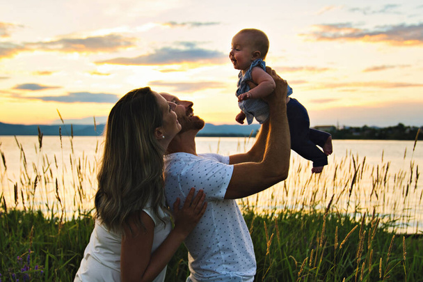 Mother father and child girl at the sunset on the waterscape - Foto, imagen