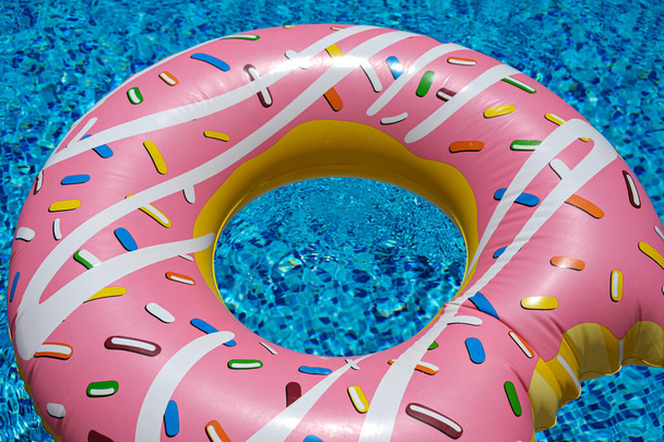 pink inflatable donut doughnut floating mattress in swimming pool. Beach pool accessories. Summer holiday concept. - Photo, Image