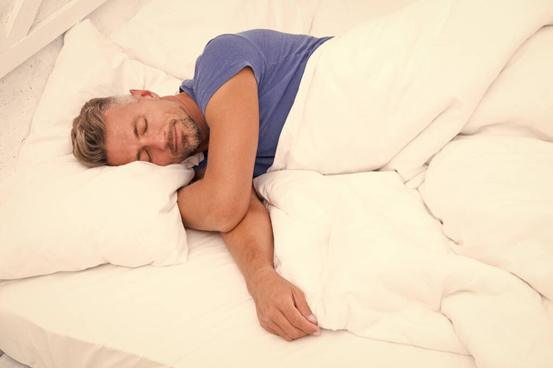 Sexy man lying on bed with soft pillows at home. Perfect morning. Tips sleeping better. male health. Enjoying time at home. Relaxing in bedroom. day dreaming male. Day sleeping. Morning of a new day - Foto, afbeelding