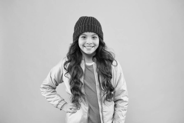cheerful child in warm winter clothes. seasonal fashion for kids. small beauty pink wall. little girl puffer jacket and knitted hat. health care in cold weather. good mood any weather - 写真・画像