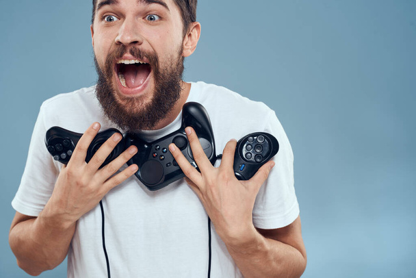 uomo tenendo gamepad giochi stile di vita tecnologia console emozioni bianco t-shirt blu sfondo - Foto, immagini