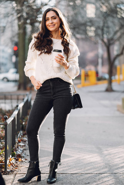 Cute brunette in a white sweater in a city - Foto, Imagem