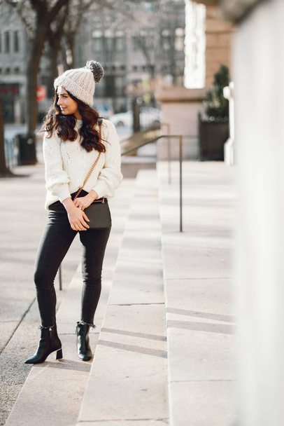 Cute brunette in a white sweater in a city - Photo, Image