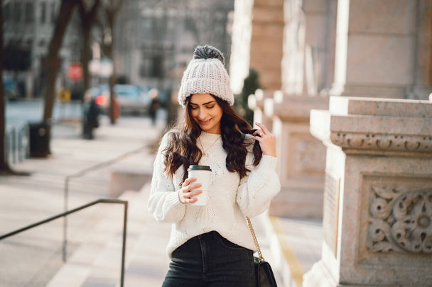 Cute brunette in a white sweater in a city - Fotografie, Obrázek