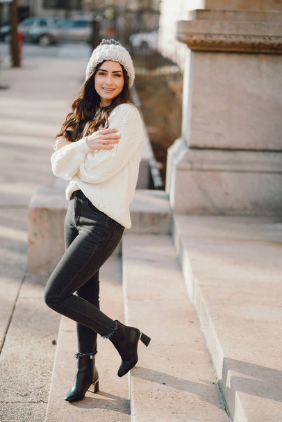 Cute brunette in a white sweater in a city - Фото, зображення