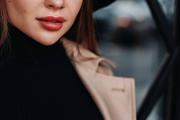 Close-up of the lips of a girl in a beige coat. Womens street fashion. Autumn clothing. - Foto, Imagem