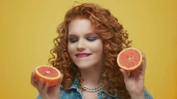 Frau bedeckt Augen mit Grapefruithälften. Mädchen mit Make-up Verkostung Grapefruit - Filmmaterial, Video