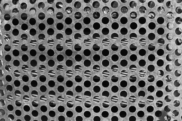 Vieille grille métallique avec trous ronds dans une texture de bâtiment abandonnée. - Photo, image