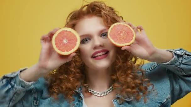 Woman holding grapefruit pieces. Girl covering face with grapefruit halves - Footage, Video