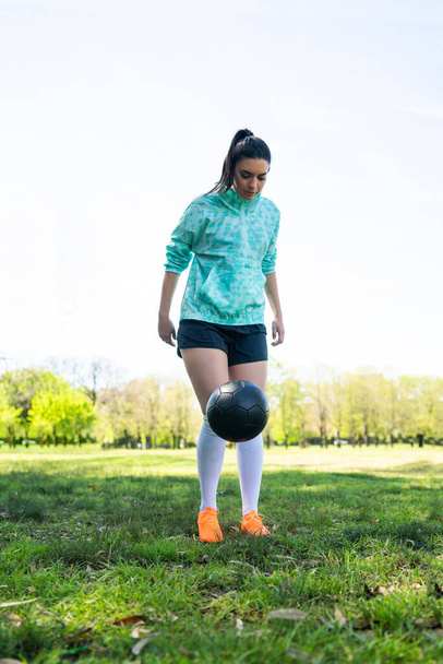 Portrait of young woman practicing soccer skills and doing tricks with the football ball. Soccer player juggling the ball. Sports concept. - Photo, image