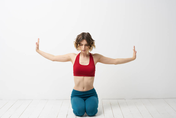 la chica se dedica al yoga sobre un fondo claro Camiseta roja gesticulando con sus manos - Foto, imagen
