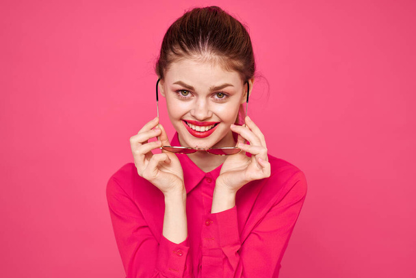 Fashion woman in pink shirt with glasses in hands on isolated background cropped view - Foto, Imagem