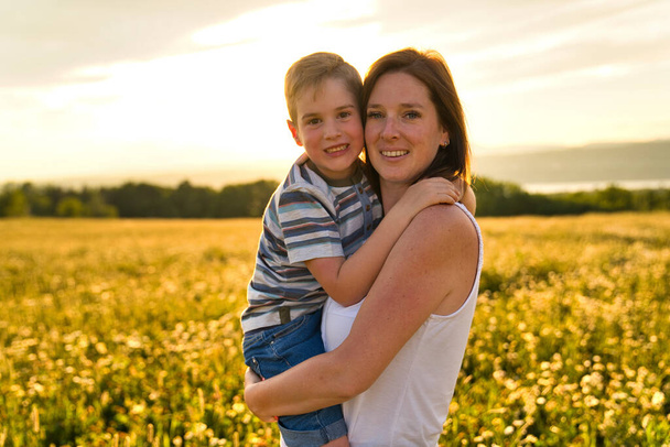 счастливая семья матери и ребенка на поле на закате весело - Фото, изображение