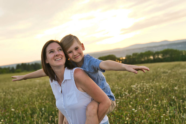 happy family of mother and child on field at the sunset having fun - Fotografie, Obrázek