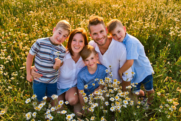 Happy family on daisy field at the sunset having great time together - Fotografie, Obrázek