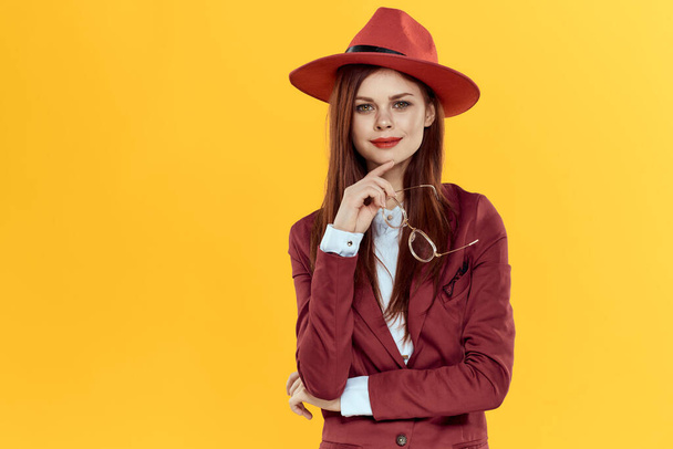 赤い帽子のジャケットの眼鏡黄色の背景化粧品の女性 - 写真・画像