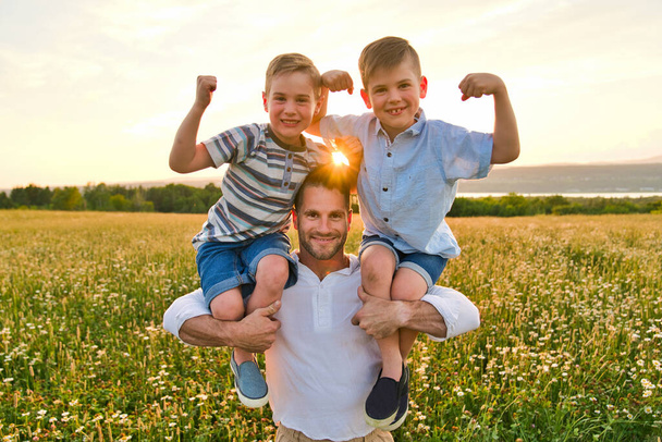 happy family of father and two childs on field at the sunset having fun, strong brother - Foto, immagini