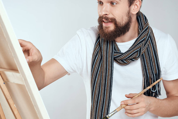 Мужчина художник рисует на мольберте шарф белой футболки художественное хобби творчество - Фото, изображение
