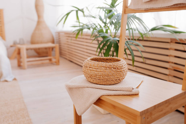 round little storage basket and natural beige towel folded on wooden table in the bathroom. the elements of bathroom decor using natural materials. Minimalism in renovation - 写真・画像