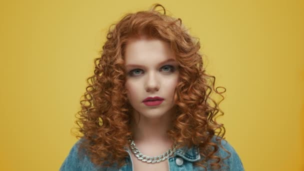 Stylish woman standing on yellow background. Girl with makeup looking at camera - Footage, Video