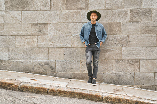 casual young man standing by a concrete wall - Fotó, kép