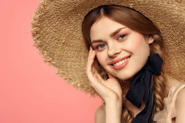 Portrait of a girl in a straw hat on a pink background emotions close-up beautiful face model pigtails - Fotó, kép