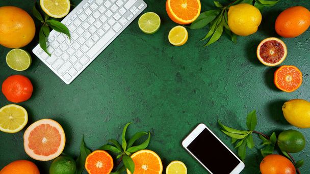 Citrus fruit on textured green background workspace blog hero header flat lay. - Fotó, kép