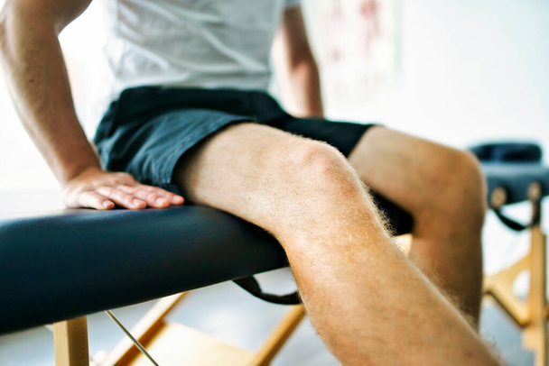 Een moderne revalidatie fysiotherapie plaats met man client zitten op tafel - Foto, afbeelding