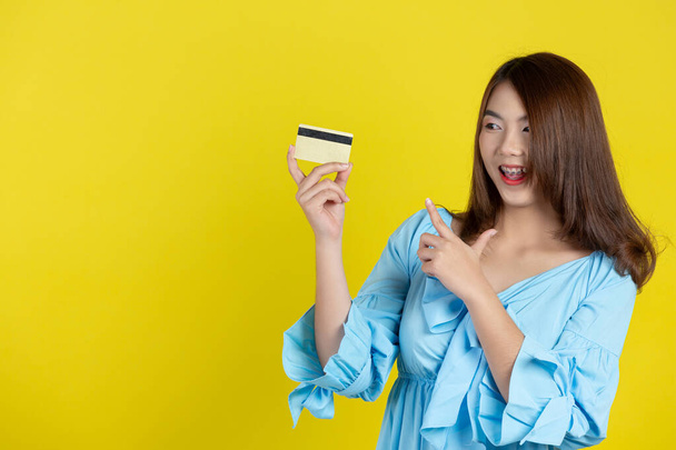  krásná asijská žena ukazující úvěr na žlutém pozadí - Fotografie, Obrázek
